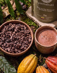 Bowl of Ceremonial Cacao chunks and a cup of cacao drink beside the 1kg bag