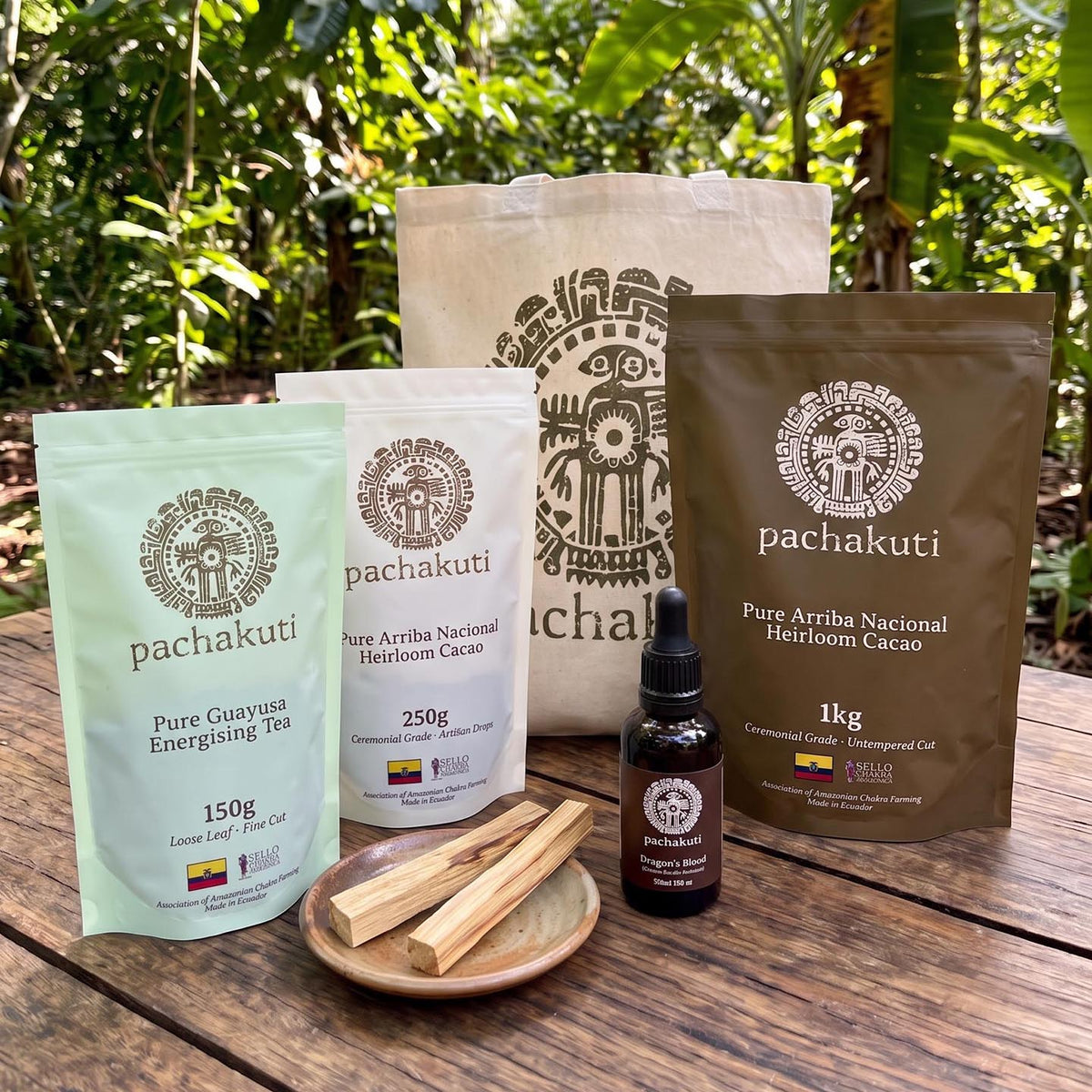 The Amazonian Apothecary Kit on a wooden table: guayusa tea, ceremonial cacao, 1kg heirloom cacao, Dragon's Blood, Palo Santo and tote bag