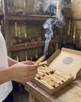 Burning Palo Santo stick held over an open box of sticks