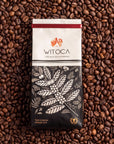 Bag of Witoca Shaman coffee on roasted coffee beans