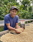 Witoca coffee farmer holding green coffee beans on a drying bed