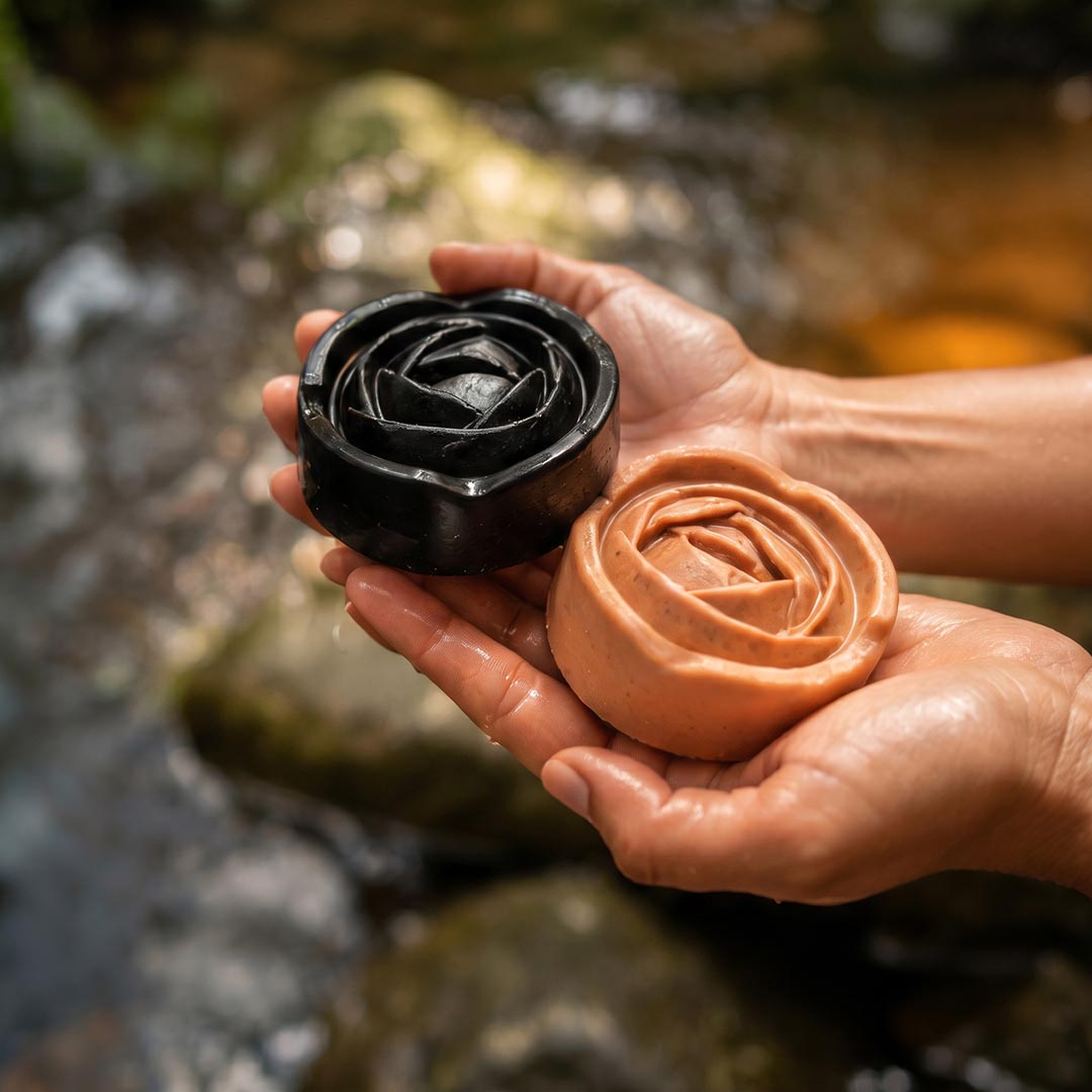 Hands holding Witoca coffee and cacao soaps by a stream