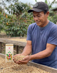 Witoca coffee farmer holding green coffee beans beside a bag of Witoca Sumak